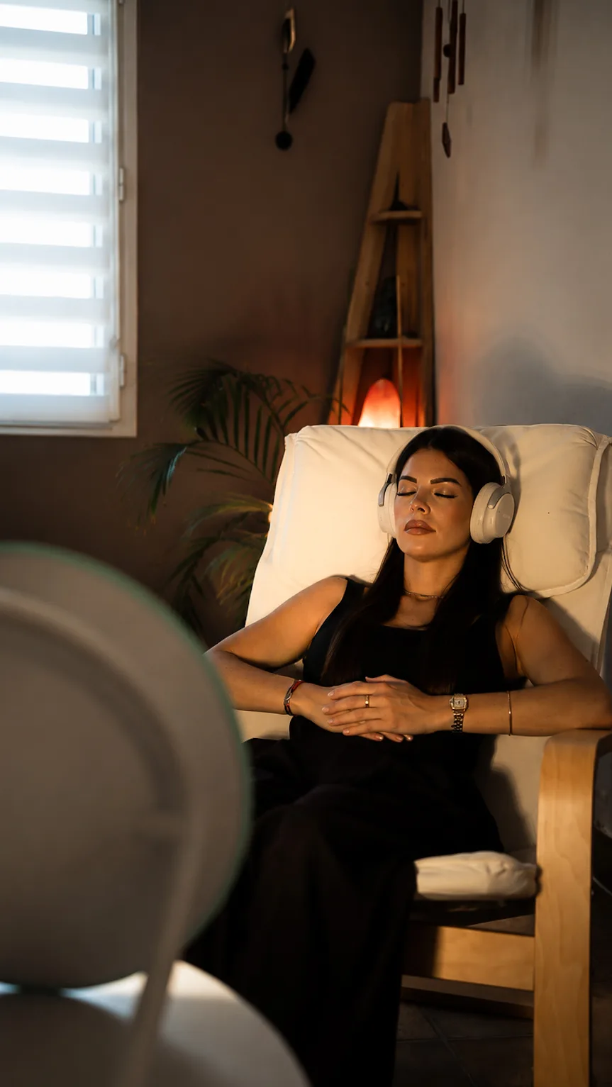 Une personne les yeux fermés, installée dans un fauteuil avec un casque audio face à la Dream Machine
